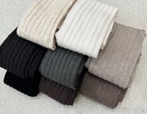 Gros plan détaillé de collants en tricot côtelé aux couleurs neutres montrant une texture douce.