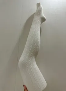 Gros plan détail collants tricotés blancs, motif rétro texturé, vêtement hiver chaud doux.