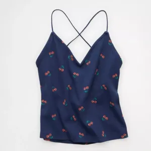Vista detallada del top azul oscuro con estampado de cerezas, cuello en V y tirantes finos.