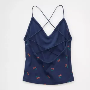 Primer plano detallado de la camiseta azul oscura con estampado de cerezas y tirantes cruzados.