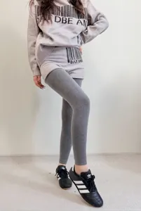 Vista detallada de leggings térmicos grises forrados de mujer combinados con jersey de punto.