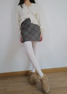 Winter fleece-lined white tights detail view, warm thermal leggings styled with plaid skirt.