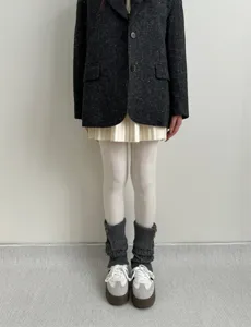 Vue détaillée de collants blancs texturés assortis de jambières en tricot gris et chaussures.