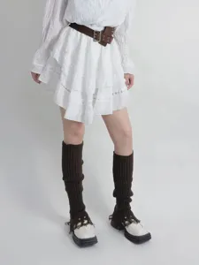 Detailed shot of brown knitted leg warmers with distressed tassel design for winter fashion style.