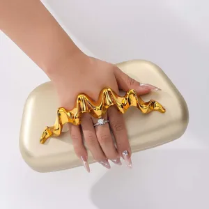 Λεπτομέρεια χρυσής τσάντας clutch με μοναδική μεταλλική κυματιστή λαβή για κομψά βραδινά ρούχα.