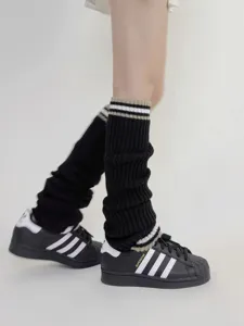 Vista dettagliata di scaldamuscoli in maglia nera con doppie righe indossati con scarpe.
