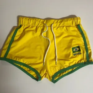 Gelbe Sportshorts mit gruenem Besatz und Brasilien Flagge Stickerei fuer den Sommer.