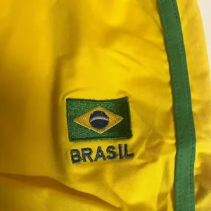 Gelbe Sportshorts Detail mit grünen Seitenstreifen und gestickter Brasilien Flagge für den Sommer