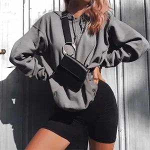 Ensemble sweat gris et short cycliste noir pour femme avec sac bandoulière stylé.