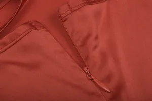 Close-up detail view of women's red satin dress zipper craftsmanship and neat stitching lines.
