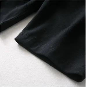 Gros plan détaillé d'un poignet de vêtement en tissu noir, montrant des coutures fines et texture.