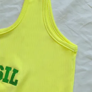 Dettaglio canotta a costine giallo neon, gilet lavorato a maglia senza maniche con ricamo verde.