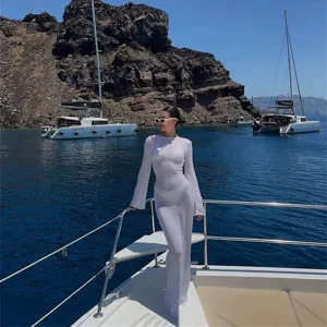 Detail view of white long sleeve sheer knit beach dress showcasing elegant resort style.