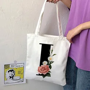 Borsa tote in tela bianca con elegante lettera I nera e stampa floreale per uso quotidiano.