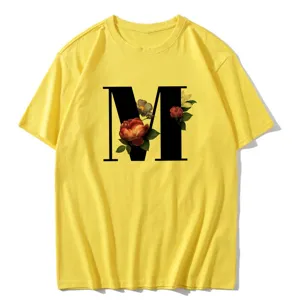Close-up detail of the vintage floral letter M print on a vibrant yellow women's t-shirt.