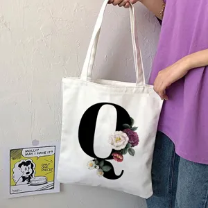 Borsa shopper in tela bianca con grande lettera Q nera e stampa floreale vintage per uso quotidiano.