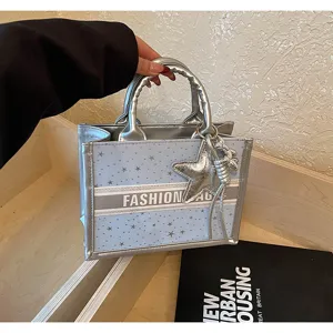 Stylish blue silver tote bag with star pattern, chic embroidered stripe and star pendant detail.