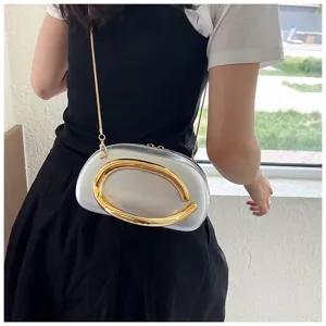 Détail de sac bandoulière rugby avec décor métallique, sac de soirée argenté chic chaîne.