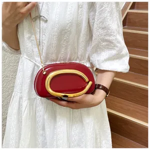 Sac bandoulière rouge style rugby avec fermoir métallique doré pour femmes élégantes.