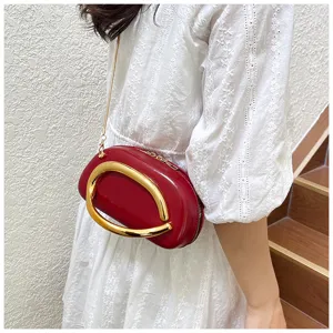 Sac bandoulière ovale rouge élégant avec poignée en métal doré et chaîne pour femme.