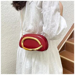 Sac bandoulière rouge en forme de rugby pour femme avec belle quincaillerie dorée.