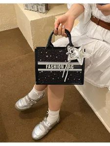 Black canvas tote bag with star pattern, horizontal band, and chic silver star charm.