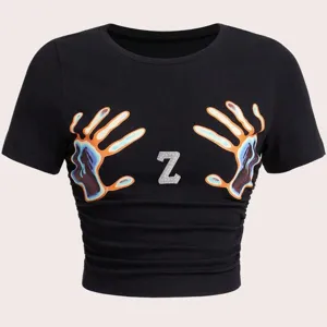 Nahaufnahme der Details eines schwarzen Crop Shirts mit Handabdrücken und funkelndem Z.
