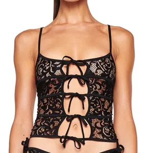 Detailed view of black lace camisole featuring front bow ties, cutout details and delicate sheer fabric.