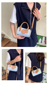 Close-up detail of stylish denim cylindrical bag featuring cute pink bow patterns.
