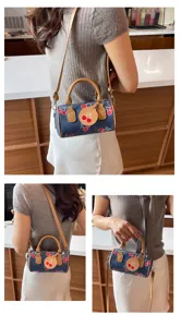 Trendy denim cherry print cylindrical shoulder bag for women, chic crossbody bag with top handle.