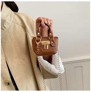 Nahaufnahme Detail der kleinen braunen Kunstleder Handtasche mit goldenem Schloss und Kette.