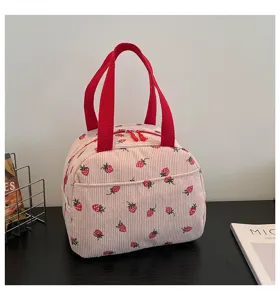 Detail der süßen Kord Erdbeer-Lunchtasche, rosa Handtasche mit leuchtend roten Henkeln.