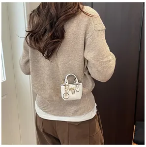 Nahaufnahme der stilvollen weißen Mini-Umhängetasche mit goldener Kette und Schloss.