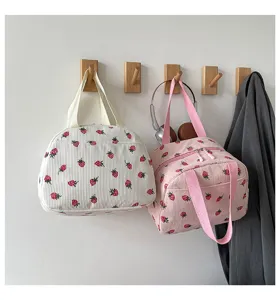 Kord-Erdbeer-Handtasche Detail, süße Freizeittasche an Holzhaken hängend im Zimmer.