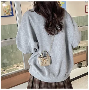 Detailaufnahme einer schicken Mini-Metallic-Umhängetasche mit Kette und Schloss-Anhänger im Einsatz.