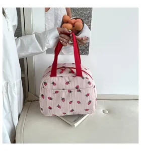 Detaillierte Nahaufnahme der rosa Kord-Lunchtasche mit süßem Erdbeermotiv und roten Henkeln.