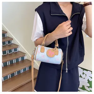 Detail view of cute denim barrel bag with pink bows, stylish shoulder strap and round charm.