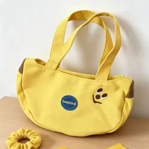 Cute yellow canvas handbag, portable commuter tote bag with embroidered face and patch.