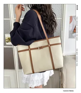Detail shot of a stylish beige and brown PU leather tote bag with vertical strap and buckle accent.