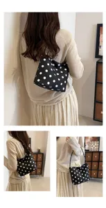Detail view of a black polka dot shoulder bag worn by a model in a stylish indoor setting.