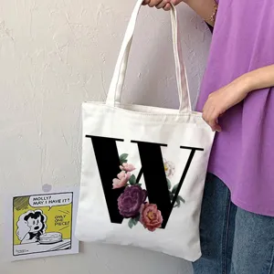 Borsa shopper in tela bianca con elegante lettera W nera e stampa floreale per uso quotidiano.