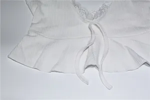 Vue détaillée du débardeur côtelé blanc avec bordure en dentelle délicate et lien.