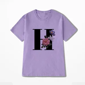 Gedetailleerd zicht op paars t-shirt met korte mouwen, zwarte letter H en bloemenprint.