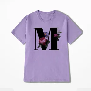 Paars t-shirt met korte mouwen en een grote zwarte letter M met bloemenprint.