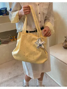 Detailed view of the yellow star print pleated tote bag with a shiny silver star pendant charm.