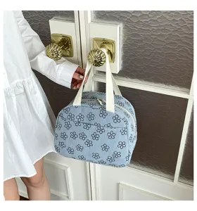 Gros plan du sac à main en velours côtelé bleu à motifs floraux avec fermeture et anses.