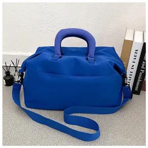 Blue fitness duffel bag detail, showing durable fabric, sturdy handles and adjustable strap.