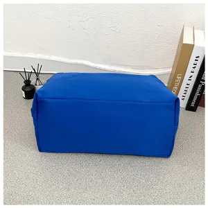 Close-up detail of a solid blue travel gym bag on a modern textured floor with decor books.