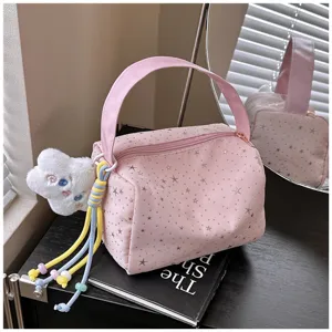 Detail view of a cute pink star pattern handbag with a plush cloud charm and top handle.