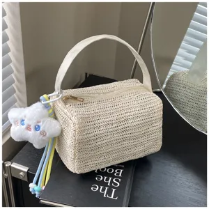 Detailed view of beige straw woven lunch box handbag with cute plush star charm for summer beach.